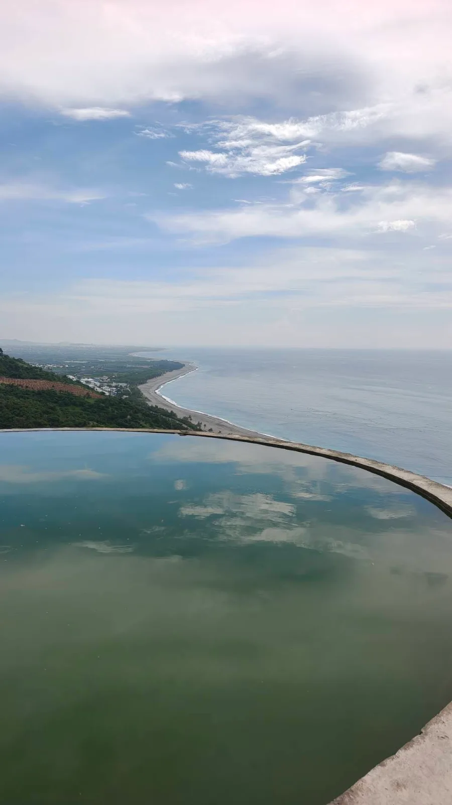 圓形蓄水池的水面映著雲,外面接著海岸(實景・五星台東旅遊自攝)